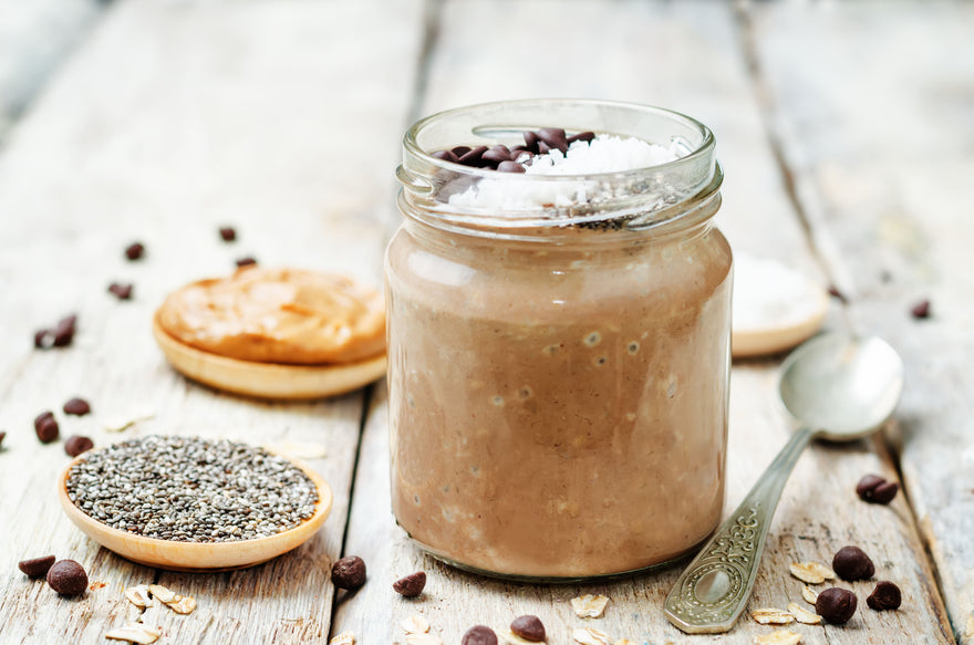 Jar of chocolate chia overnight oats garnished with coconut and chocolate chips