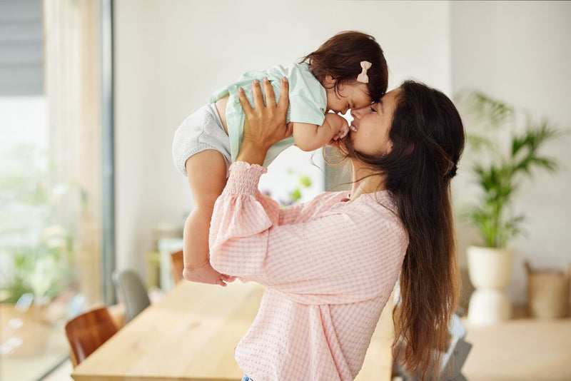 Mom in pink shirt lifting her child above