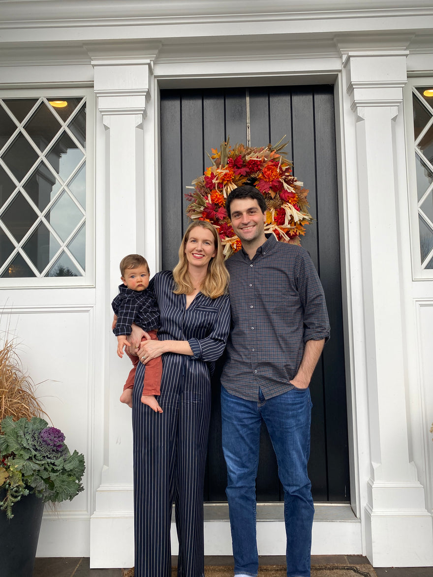 Lauren's family dressed in grey, standing next to each other smiling, in front of their front door.