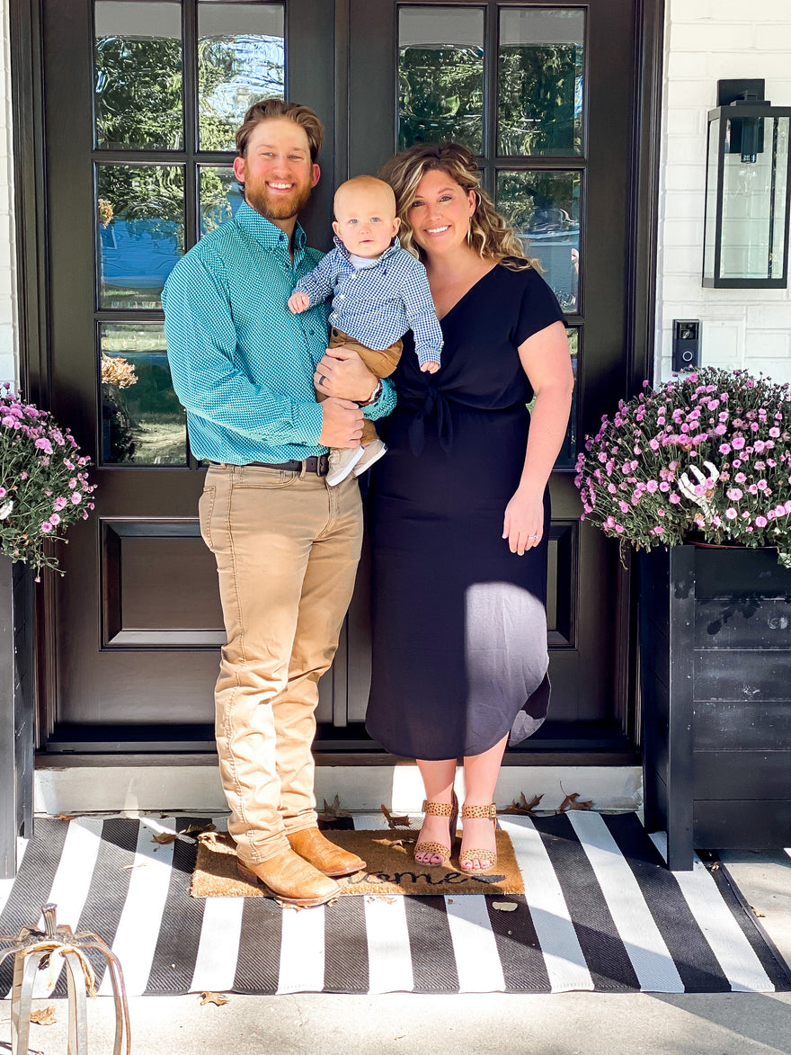 Happy family of three standing and smiling outside on their front entrance.