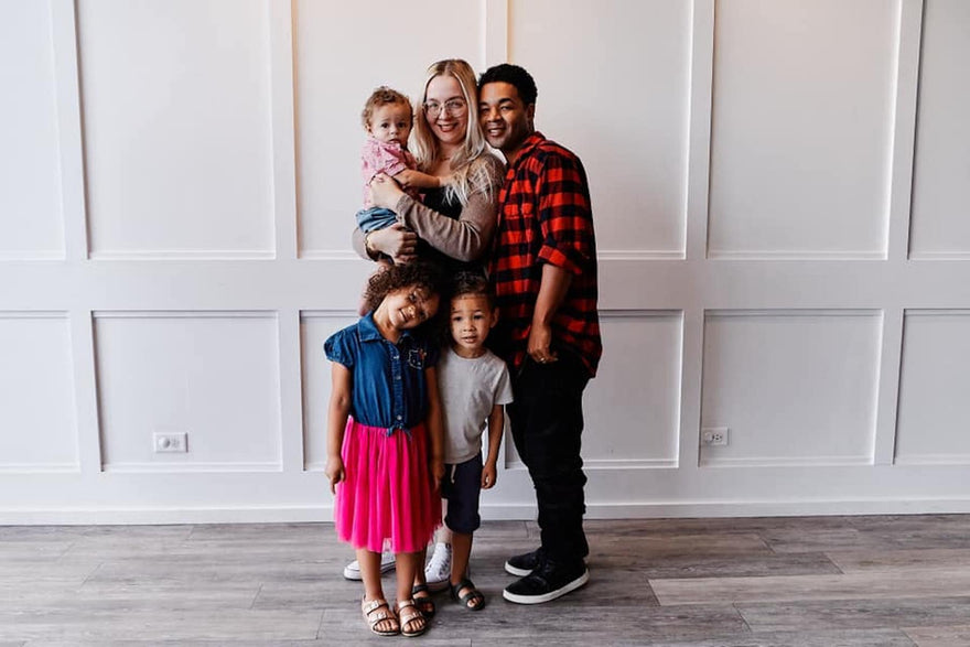 Monique's Family standing in front of a white wall