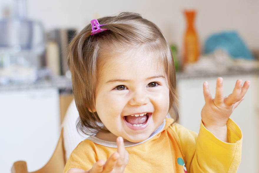 Smiling toddler raising her hands up with joy
