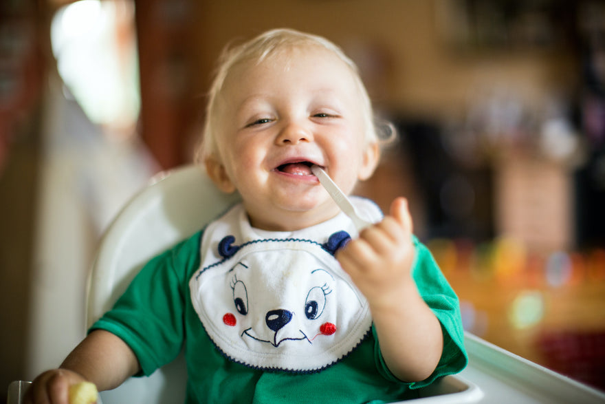 Toddler smiling and playing with spoon