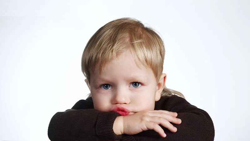 Blond haired toddler boy pouting with crossed arms