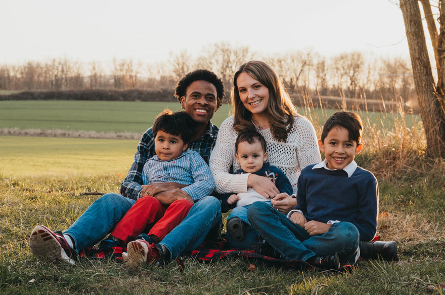 Happy family of 5 sitting in a field outside