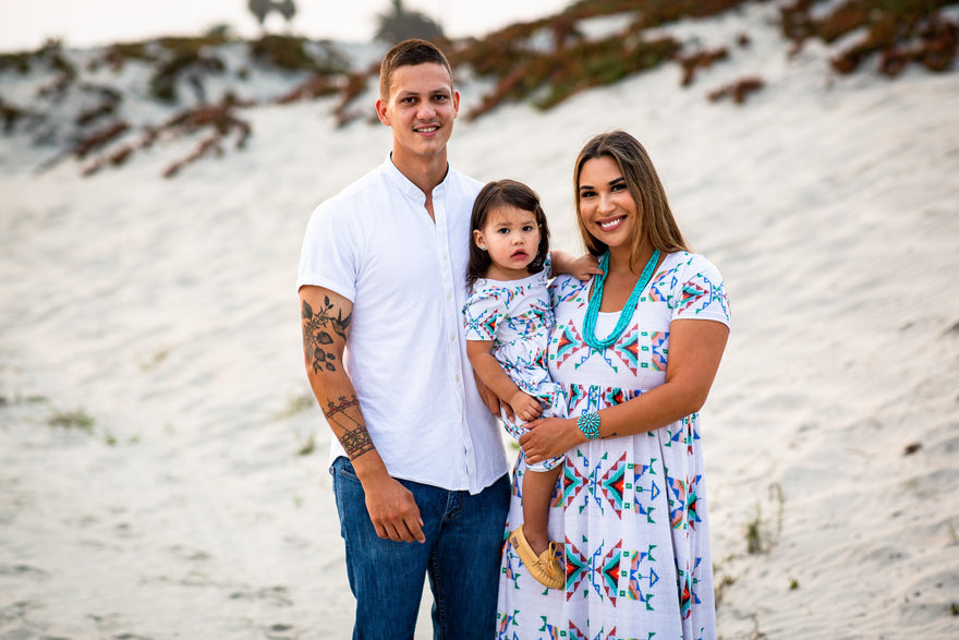 Happy, smiling indigenous family of three standing outside in nature