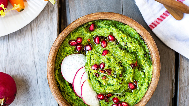 Spinach Hummus in a bowl with radishes and pomegranate seeds
