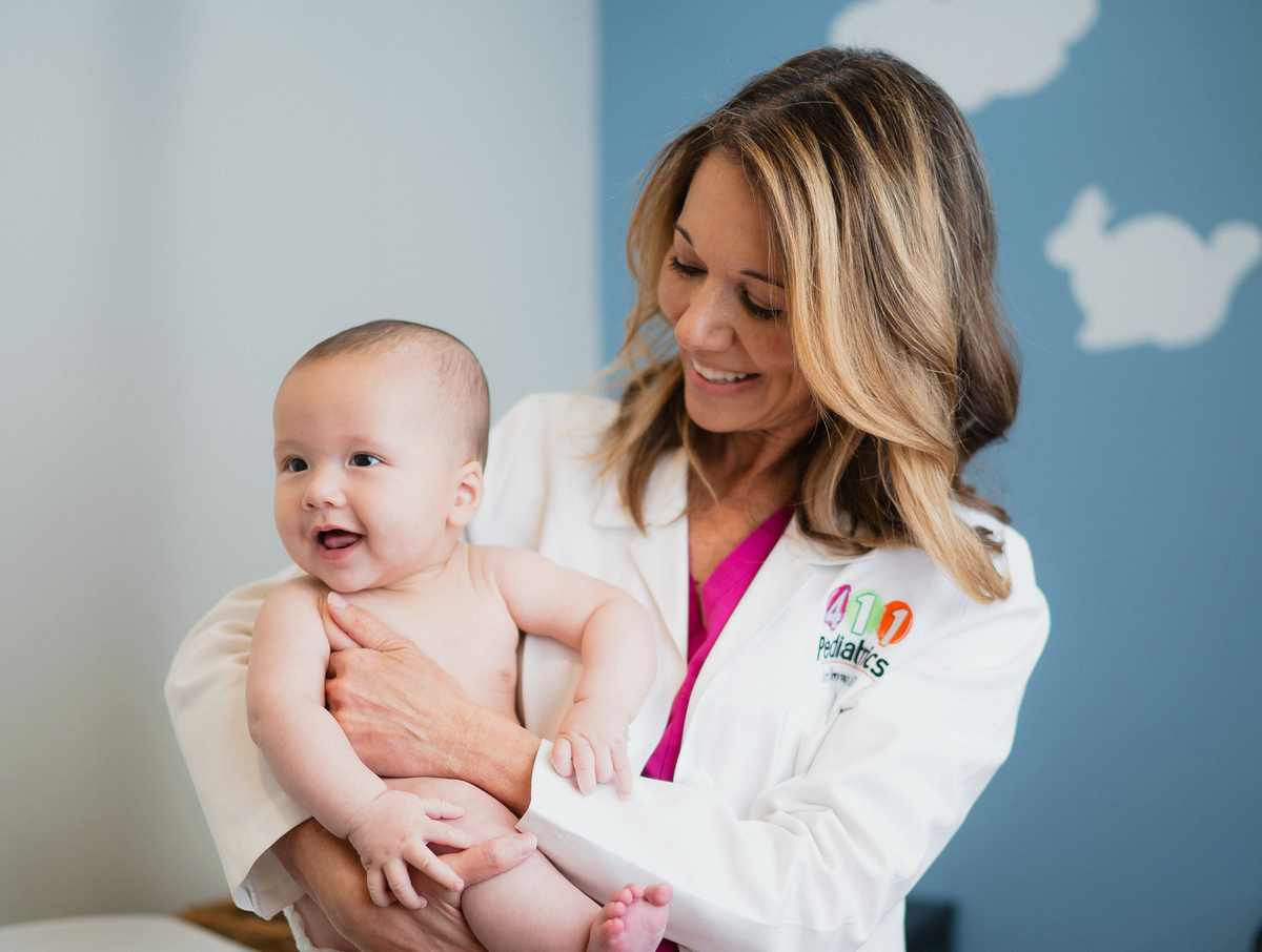 Doctor Ari holding a baby in a medical office setting